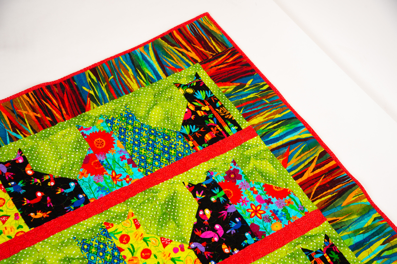 Close up photo of a quilt with a cat pattern. 