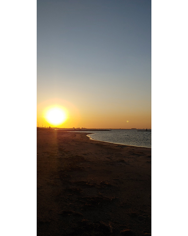 Color photograph of a sunset over a shoreline.