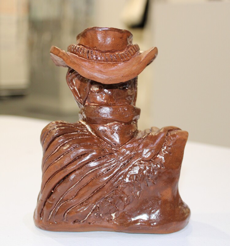 Ceramic bust of a figure with a cowboy hat and bandana.
