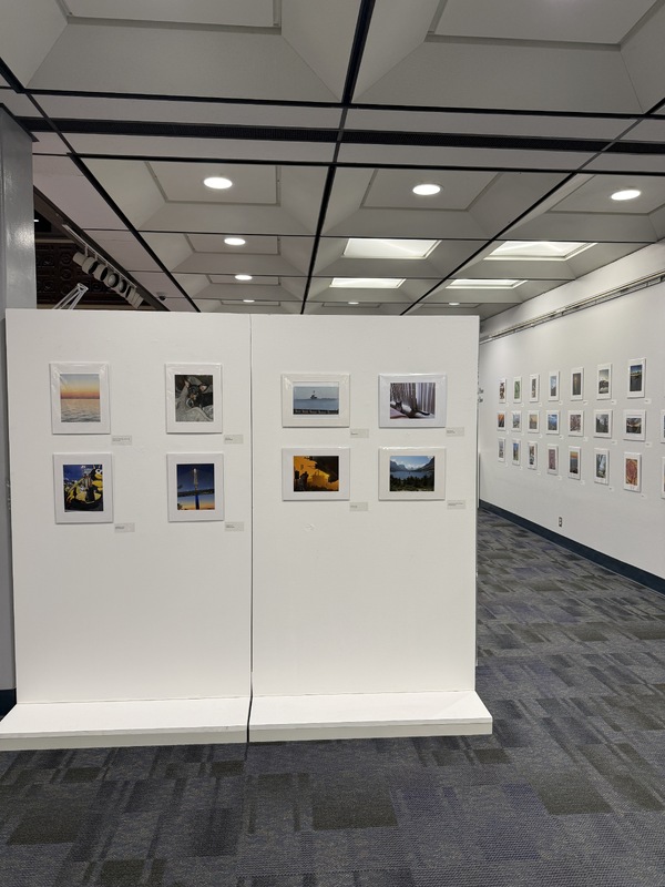 Interior view of a photographic exhibition featuring framed photographs on white walls.