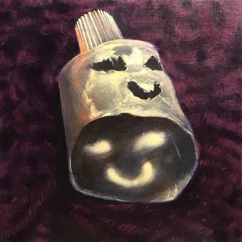 Artist: David Hill. 11 by 11-inch Acrylic on canvas stretched wood panel titled, Sphinx. The top of a tube (with the cap on) rests of a bed of purple yarn. The tube has been cut and emptied, with eyes and a smiling mouth cut out of the tube. The perspective allows light to shine through the tube surface and reflect on the inside of the tube.