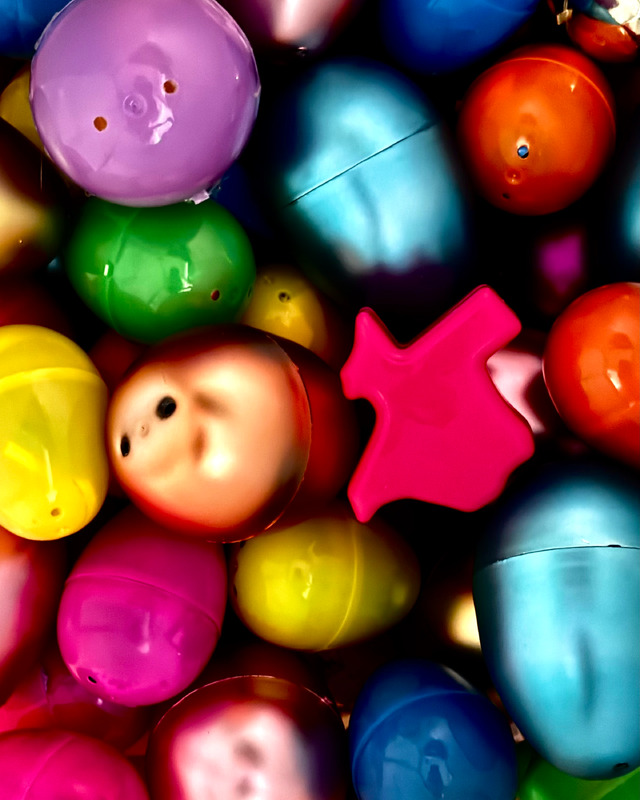 A vibrant collection of colorful plastic eggs in various shades, with a bright pink Texas-shaped object among them.