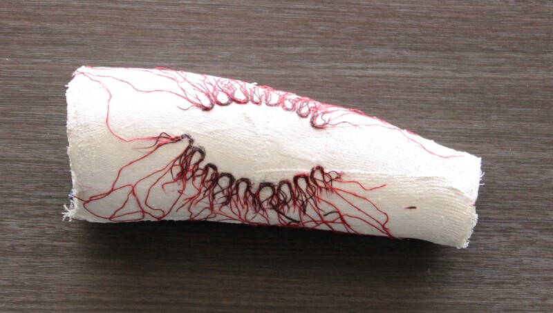Plaster cast with teeth marks crafted from dark red thread.