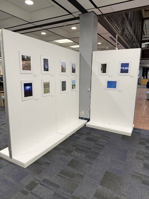 Interior view of a photographic exhibition featuring framed photographs on white walls.