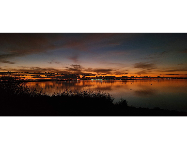 Color photograph of a sunrise over a body of water