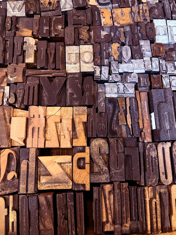 Collection of physical types, including numbers and letters in a variety of sizes. The types are laid out flat, edge to edge, to create a block of types.