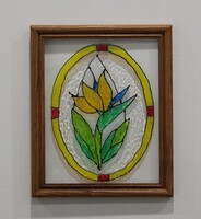 Stained glass art with a yellow flower and green leaves in a wooden frame.
