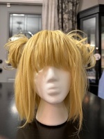 Artist: Phebe Raglin. 10 by 11-inch blond wig. The hairpiece is fashioned with an angled bob cut, straight bangs and small side buns on each side of the head.