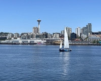 A sailboat on water with a city skyline and the Space Needle in the background.
