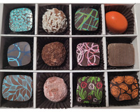 A box of twelve assorted chocolates arranged in three rows, featuring various shapes, colors, and decorative patterns.