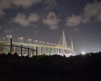 Night view of a suspension bridge with illuminated towers and streetlights.