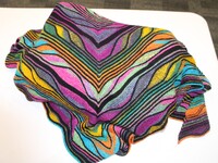 A colorful knitted fabric with V-shaped stripes in black, pink, purple, yellow, green, blue, and orange draped on a white surface.
