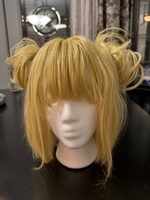 Artist: Phebe Raglin. 10 by 11-inch blond wig. The hairpiece is fashioned with an angled bob cut, straight bangs and small side buns on each side of the head.