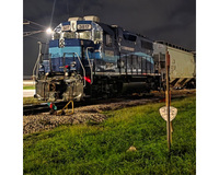 A blue and black locomotive numbered 3817 at night on railway tracks with a freight car in the background.