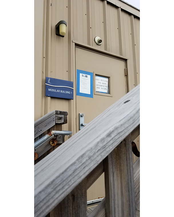 Color photograph of signage posted in the window of a building door. The sign reads "This building has been disinfected and secured."