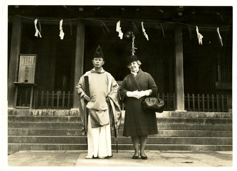 A man in traditional Japanese clothing and a woman in Western attire stand on steps outside a building.