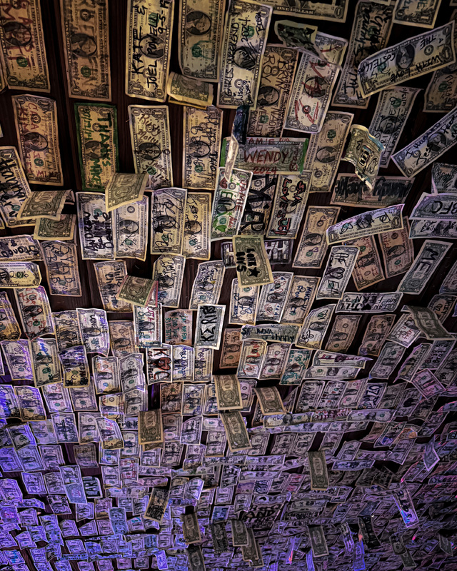 Ceiling covered with U.S. dollar bills, each featuring various handwritten messages and doodles.