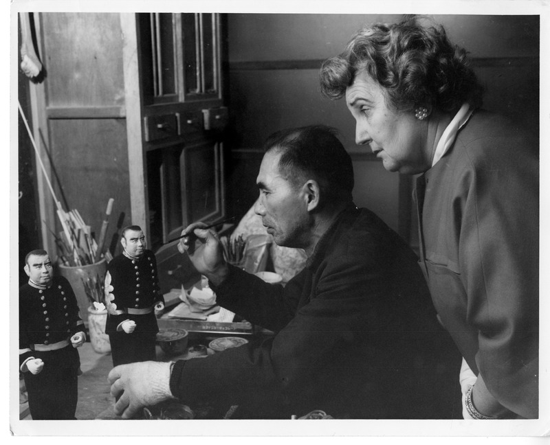 Man painting a figurine with a woman observing in an art workshop.