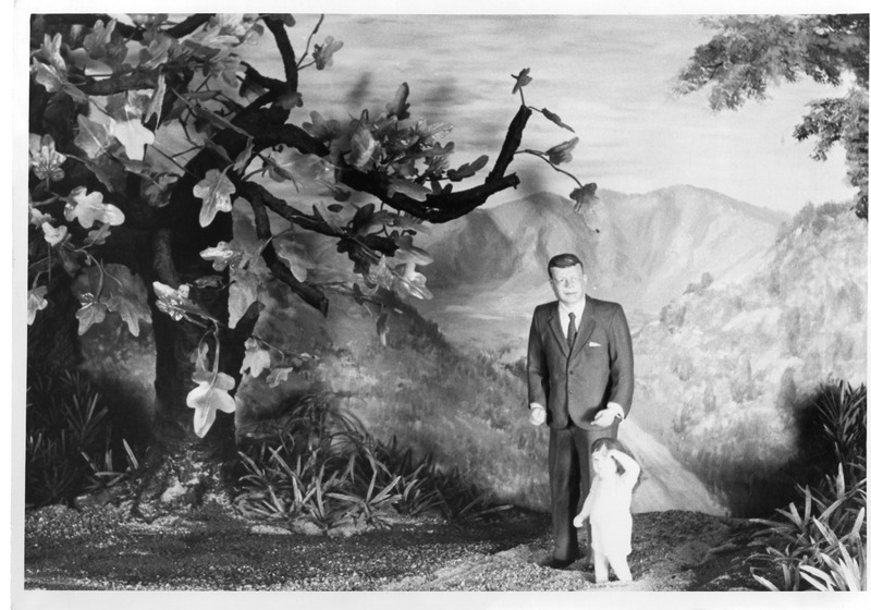 Figure of a man in a suit with a child in an artificial forest setting.