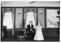 Dolls in formal attire in an elegant room with draped windows and a painting of a snowy landscape.