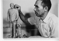 A man sculpting a statue of a man in a suit with a child beside it.