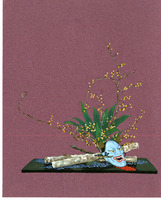 Still-life arrangement with a blue mask, budding branches, and textured objects on a dark platform.