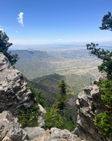 View from a high point overlooking rocky cliffs and a forested valley under a clear sky.