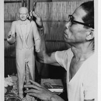 Man sculpting a detailed figurine of a man in a suit.