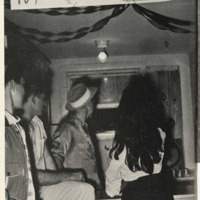 A young woman throws a dart at a school function. The hand written sign shows it is 10 cents and says '(NO CREDIT)'