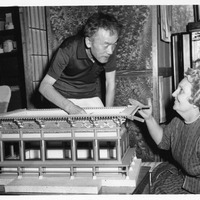 Two people examine an architectural model of a traditional Asian building.