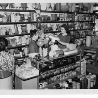 Store interior with shelves of pottery; a woman assists customers at the counter.
