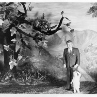 Figure of a man in a suit with a child in an artificial forest setting.