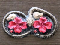 Sculpted snake surrounding skulls and red flowers